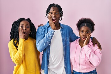 Canvas Print - Group of three young black people standing together over pink background afraid and shocked, surprise and amazed expression with hands on face