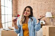 © Krakenimages.com - Young hispanic woman holding pregnancy test result at new home smiling happy pointing with hand and finger to the side