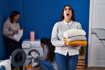 Sticker - Three women doing laundry at home angry and mad screaming frustrated and furious, shouting with anger looking up.