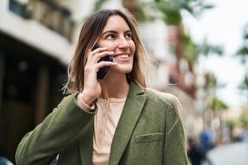 Wall Mural - Young woman smiling confident talking on the smartphone at street