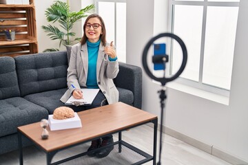 Poster - Middle age hispanic woman working at therapy office online smiling happy and positive, thumb up doing excellent and approval sign