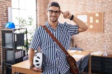 Sticker - Hispanic man with long hair working at the office holding bike helmet smiling pointing to head with one finger, great idea or thought, good memory