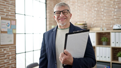 Poster - Middle age grey-haired man business worker smiling confident holding checklist at office