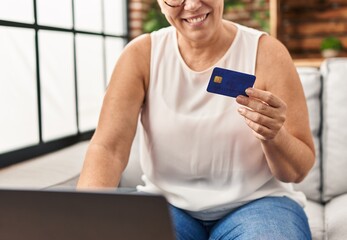 Wall Mural - Middle age woman using laptop and credit card at home