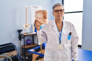 Poster - Middle age woman holding cervical neck collar looking positive and happy standing and smiling with a confident smile showing teeth