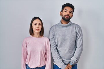 Wall Mural - Young hispanic couple standing together relaxed with serious expression on face. simple and natural looking at the camera.