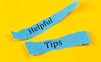 HELPFUL TIPS text on a blue pieces of paper on yellow background, business concept
