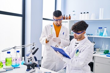 Sticker - Two man scientists holding test tubes write on clipboard working at laboratory