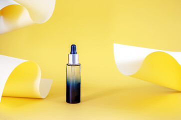  bottle with an essential oil pipette on an abstract background made of colored yellow paper