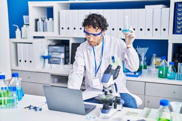 Sticker - Young hispanic man scientist using laptop holding test tube at laboratory