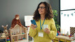 © Krakenimages.com - Middle age hispanic woman preschool teacher using smartphone drinking coffee at kindergarten