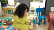 © Krakenimages.com - Middle age hispanic woman preschool teacher stressed sitting on chair at kindergarten