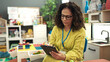 © Krakenimages.com - Middle age hispanic woman preschool teacher using touchpad at kindergarten