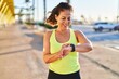 © Krakenimages.com - Middle age hispanic woman working out with smart watch at promenade