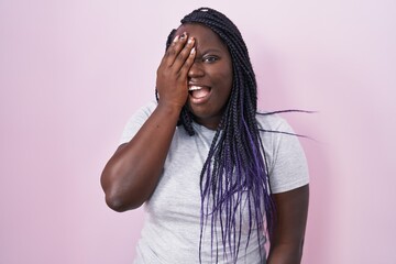 Poster - Young african woman standing over pink background yawning tired covering half face, eye and mouth with hand. face hurts in pain.