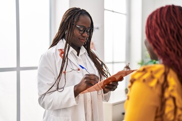 Poster - African american women doctor and patient having consultation writing medical report at clinic