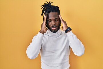 Poster - African man with dreadlocks wearing turtleneck sweater over yellow background with hand on head, headache because stress. suffering migraine.