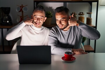 Sticker - Homosexual couple using computer laptop smiling doing phone gesture with hand and fingers like talking on the telephone. communicating concepts.