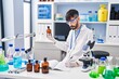 © Krakenimages.com - Young hispanic man scientist writing on notebook holding bottle at laboratory