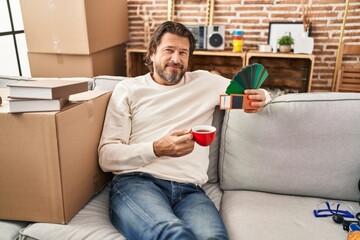 Sticker - Middle age man drinking coffee holding test color paint at new home