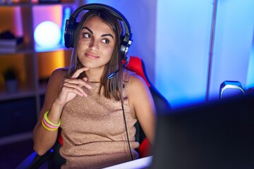 Poster - Young beautiful hispanic woman streamer smiling confident sitting on table at gaming room