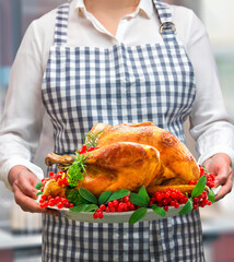 Wall Mural - Woman holds golden roasted Christmas or Thanksgiving turkey
