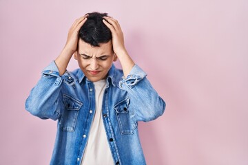 Poster - Non binary person standing over pink background suffering from headache desperate and stressed because pain and migraine. hands on head.