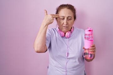 Sticker - Senior woman wearing sportswear and headphones shooting and killing oneself pointing hand and fingers to head like gun, suicide gesture.