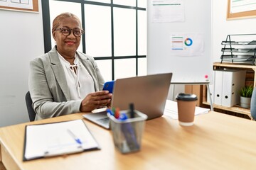 Wall Mural - Senior african american woman business worker using smartphone working at office