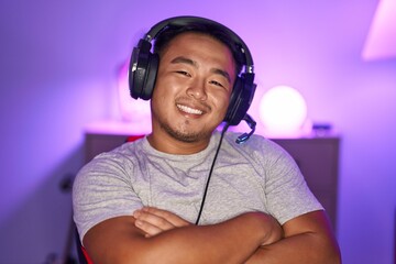 Poster - Chinese young man playing video games wearing headphones happy face smiling with crossed arms looking at the camera. positive person.