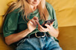 © Ilona - A woman sitting at home on the couch communicates online using a mobile phone.