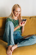 © Ilona - A woman sitting at home on the couch communicates in a mobile application.