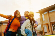Multiracial Group Of Young Girls Having Fun Leaving Class On College Campus. Female Friends Laughing Together At Sunset. Unity And Friendship Concept.