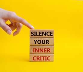 Silence your inner critic symbol. Wooden blocks with words Silence your inner critic. Beautiful yellow background. Businessman hand. Business and Silence your inner critic concept. Copy space.
