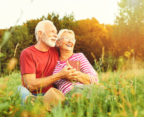 Wall Mural - woman man outdoor senior couple happy lifestyle retirement together smiling love reading nature book sitting grass