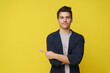 Handsome 20s young man point by finger left side with happy face looking at camera on yellow isolated background