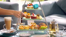 Woman Hand Take Slice Of Cake From A Towering Display Of Afternoon Tea