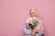 © Taras Grebinets - Smiling Arab Muslim pretty woman in pink hijab with a bouquet of chamomiles, expressing positive emotions looking at camera, on isolated pink color background. Islamic Middle-Eastern female fashion
