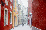 Fototapeta Uliczki - Riga old town small narrow streets during snowy weather conditions with colourful walls and snow covered pavement