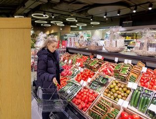 Wall Mural - Woman buying vegetables(tomatoes and cucumbers) at the market