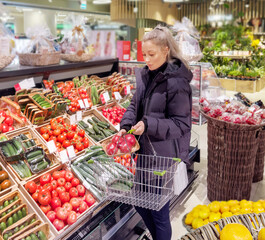 Wall Mural - Woman buying vegetables(tomatoes and cucumbers) at the market