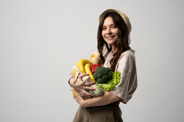 Wall Mural - Young woman holding mesh grocery bag with vegetables Concept of no plastic. Zero waste, plastic free. Eco friendly concept. Sustainable lifestyle.