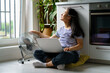 © DimaBerlin - Carefree positive Asian female copywriter working sits in kitchen on floor with laptop and pointing fan at herself. Relaxed Chinese girl enjoys distance work in comfortable. Summertime.