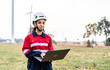 © TeTe Song - Black african american woman engineer in uniform using laptop working stand near wind turbines farm, ecological energy industry, Environmental friendly for the future