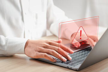 Businessman using laptop with warning sign for error notification. Maintenance concept.