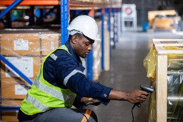 Wall Mural - Black man professional worker wearing safety uniform and hard hat worker scanning box inspect product on shelves in warehouse. Male worker is pointing finger inspecting product in factory.