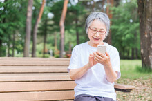 公園でスマホを使う高齢者女性（アプリ・操作・検索・写真・カメラ）
