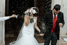 People Throw Rice On Newlyweds Walking Out Of The Church
