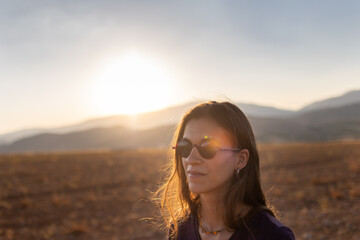 Wall Mural - portrait of a beautiful young girl in glasses on a walk in the mountains. travel in the mountains at sunset.