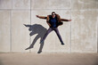 © baranq - Excited man jumping against concrete wall wearing coat during sunny afternoon